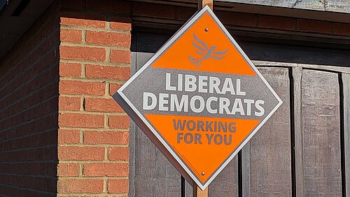 A orange, diamond shaped poster reading "Liberal Democrats" and "Working for you"