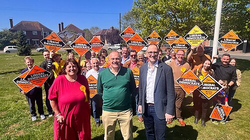Ed Davey with Liberal Democrat activists holding orange diamond placards