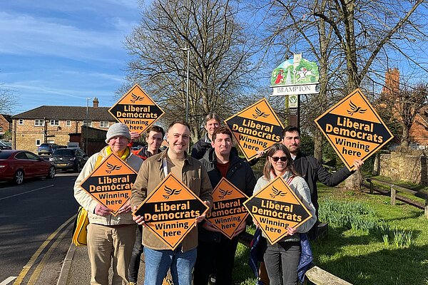 Liam Beckett with a team of activists holding orange Lib Dem diamond placards