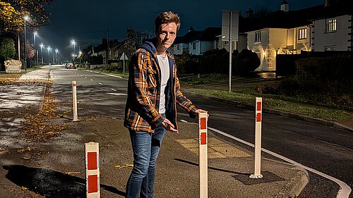 Cllr Nathan Hunt standing by traffic calming bollards, with new red reflectors