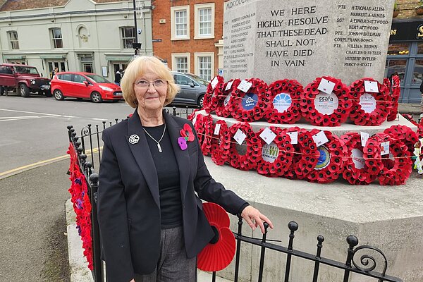 Cllr Cath Gleadow stood in front of a war memorial with wreaths